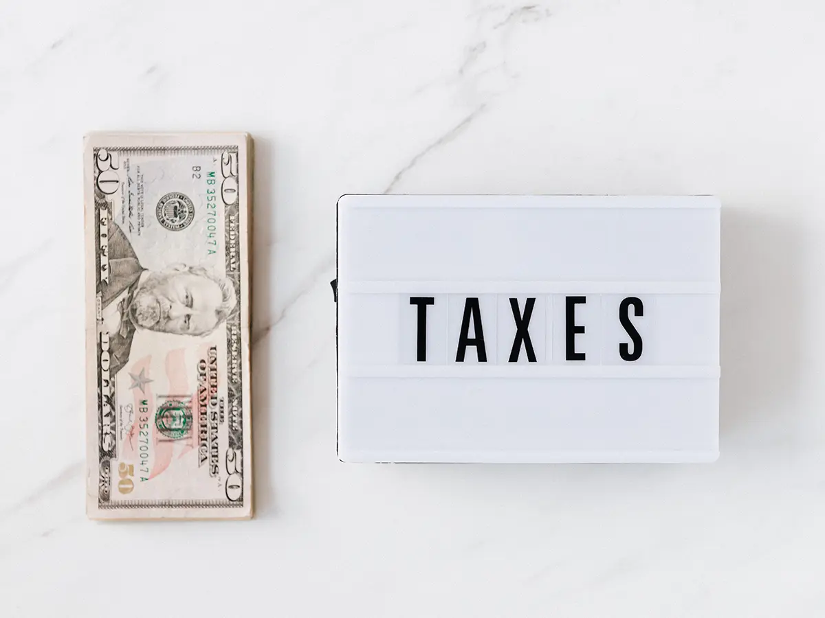 dollar bills next to a taxes sign