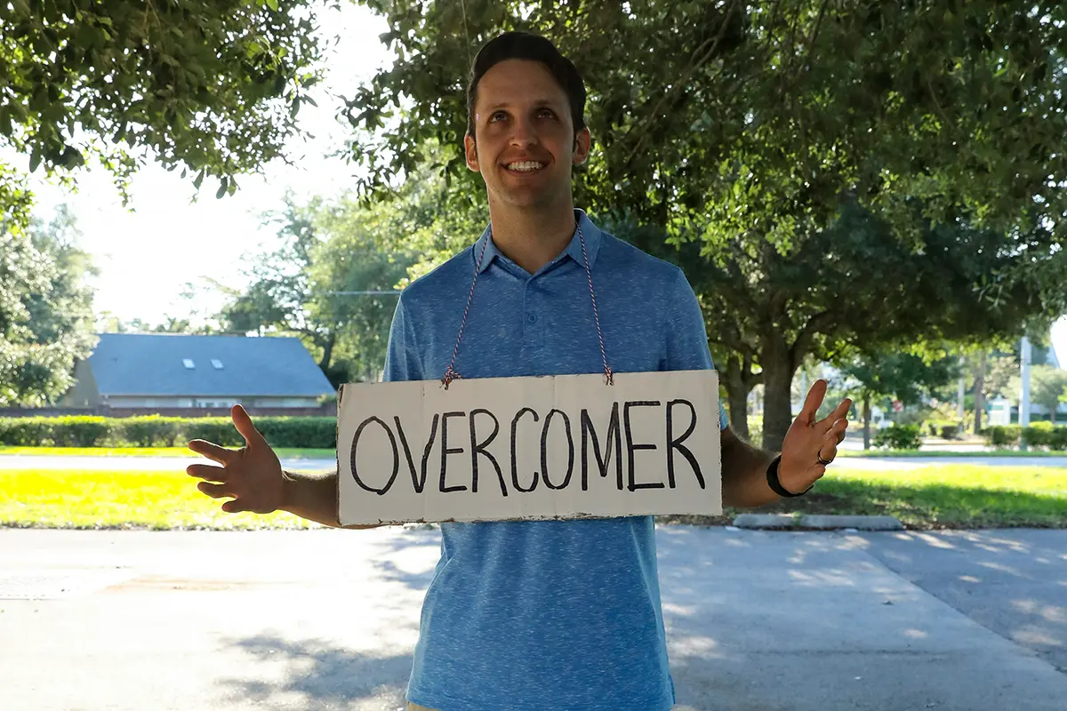 overcomer sign hanging around a persons neck